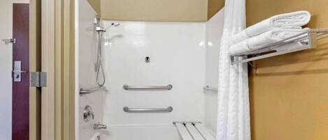 A modern bathroom with a bathtub, shower, and towel rack.