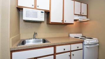 A kitchen with a microwave, stove, sink, and wooden cabinets.