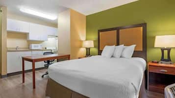 Een hotelkamer met een bed, nachtkastjes, een bureau, een magnetron en een kitchenette.