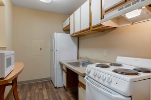 A compact kitchen with a refrigerator, microwave, sink, and stove.