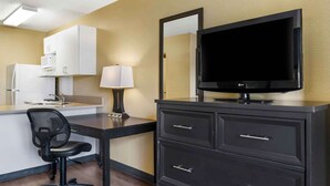 Une chambre d’hôtel équipée d’un bureau, d’une chaise, d’une télévision, d’une lampe, d’un miroir et d’un mini-bar.