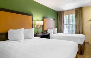 A hotel room with two beds, a nightstand with a lamp, a phone, and a window with curtains. - Extended Stay America Select Suites Raleigh RDU Airport (Morrisville)