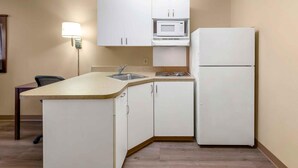A compact kitchen with white cabinets, a microwave, and a refrigerator. - Extended Stay America Select Suites Raleigh RDU Airport (Morrisville)