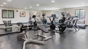 A gym with various exercise equipment, a bench, and a large mirror. - Extended Stay America Suites Arlington Six Flags (Arlington)