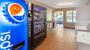 A vending machine with a Pepsi logo, a water dispenser, and a table with chairs. - Extended Stay America Suites Durham University (Durham)