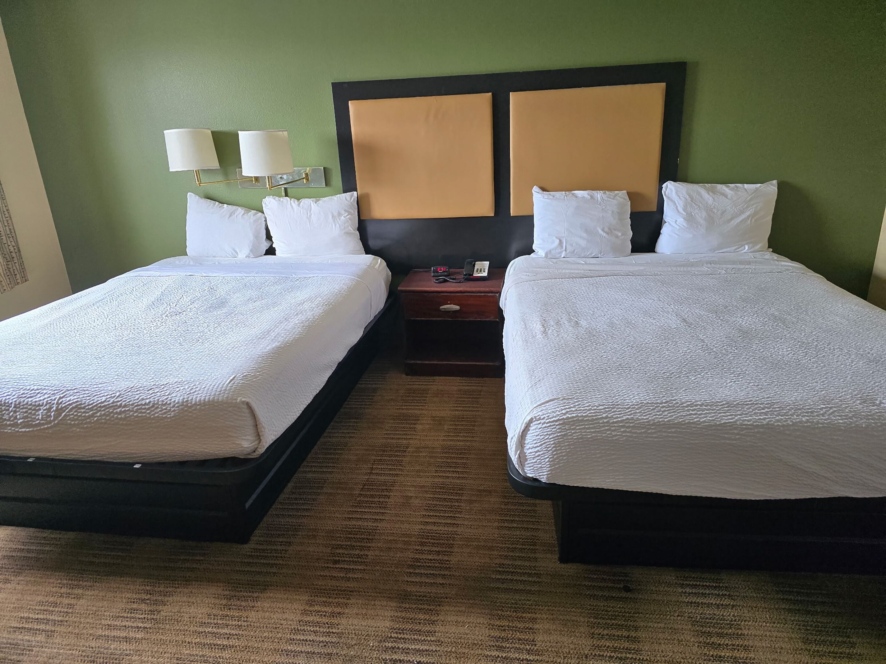 Habitación de hotel con dos camas, una mesita de noche, una lámpara y un teléfono.