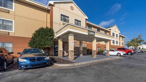 A hotel with a 'Lobby' sign, a parking lot, and a building facade with a beige and brown color scheme. - Suburban Studios (Oklahoma City)