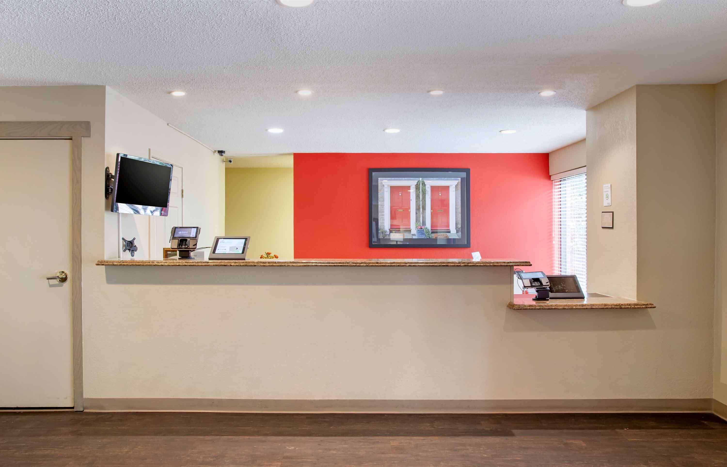 A reception area with a counter, a television, and a window with blinds.