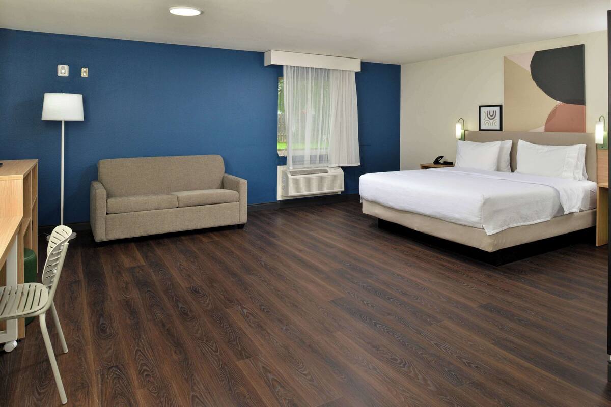 A hotel room with a bed, a sofa, a desk, and a chair.