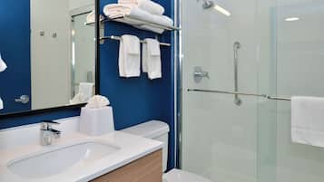 A modern bathroom with a glass-enclosed shower, white fixtures, and blue walls.