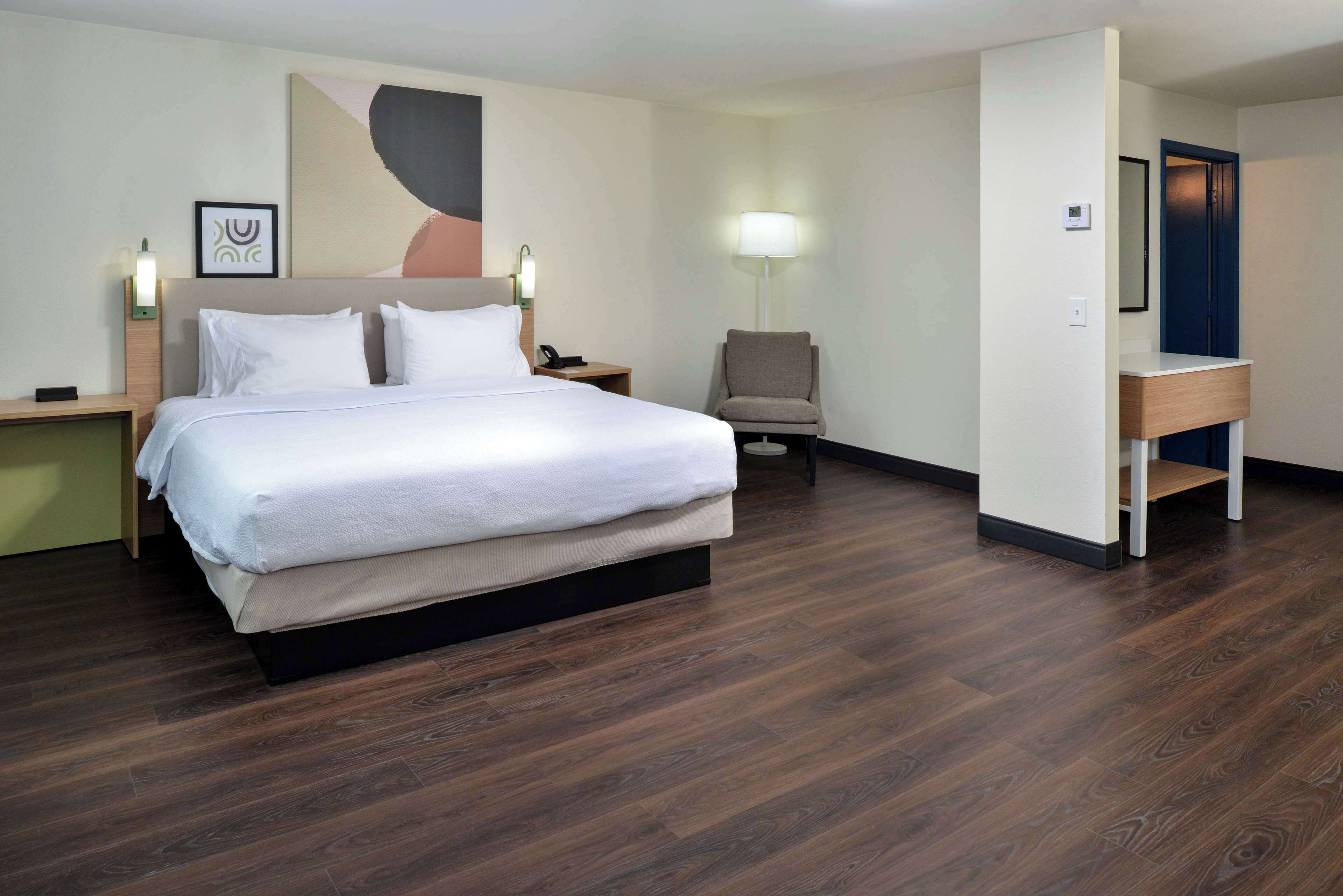 Ein Hotelzimmer mit einem großen Bett, einem Schreibtisch, einem Stuhl und einer Lampe.