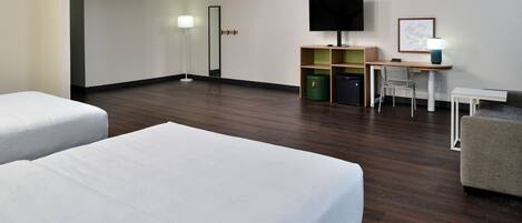 Habitación de hotel con dos camas, un escritorio, una silla, un televisor y una lámpara.