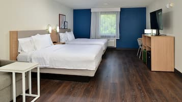 A hotel room with two beds, a TV, a desk, and a window with curtains.