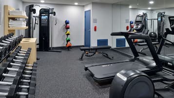 Un gimnasio con cintas de correr, máquinas de pesas y una bicicleta estática de pared.