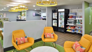 A modern interior with yellow rocking chairs, a white round table, and a vending machine area. - Spark by Hilton Dallas Medical District Love Field (Dallas)
