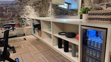 Un gimnasio en casa con una máquina de remo, estanterías de almacenamiento y un dispensador de agua.