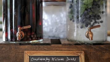 Two glass jars with metal lids, one containing blueberries and mint, and the other with a dark liquid. A chalkboard sign lists available drinks.