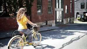 Eine Person fährt Fahrrad mit Korb auf einer Straße.