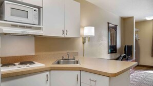 Una cocina compacta con microondas, estufa, lavaplatos y un refrigerador pequeño.