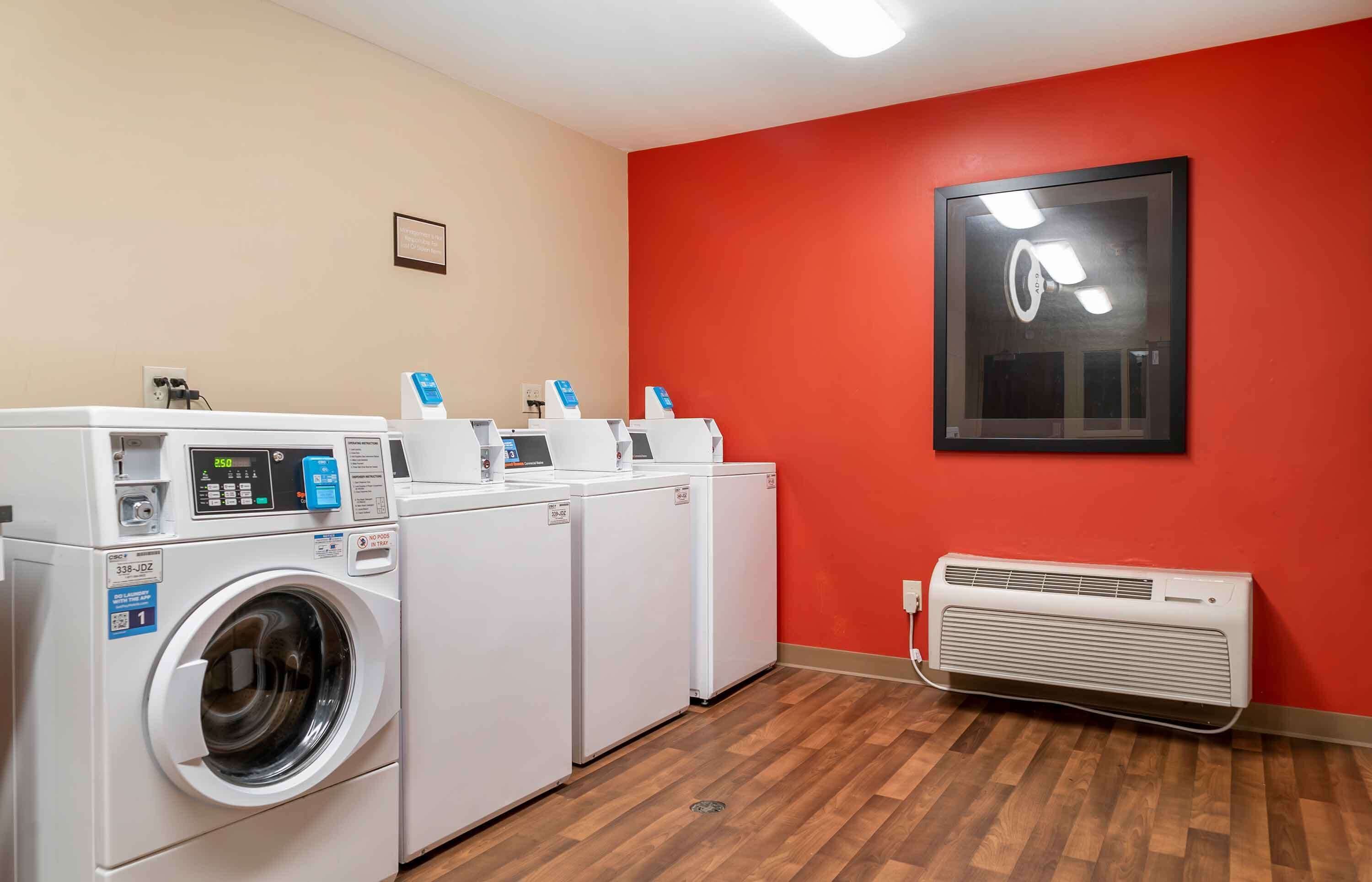 A laundry room with a washing machine, dryer, and a wall-mounted air conditioner.
