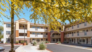Ein mehrstöckiges Hotel mit einer zentralen Lobby, Parkplätzen im Freien und Grünflächen.