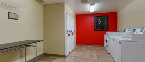 A laundry room with a washing machine, dryer, and a table with a chair.