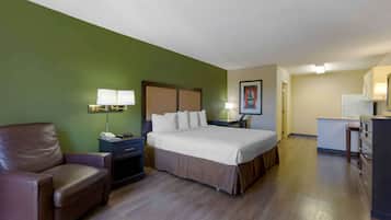 A hotel room with a bed, a desk, a chair, and a kitchenette.