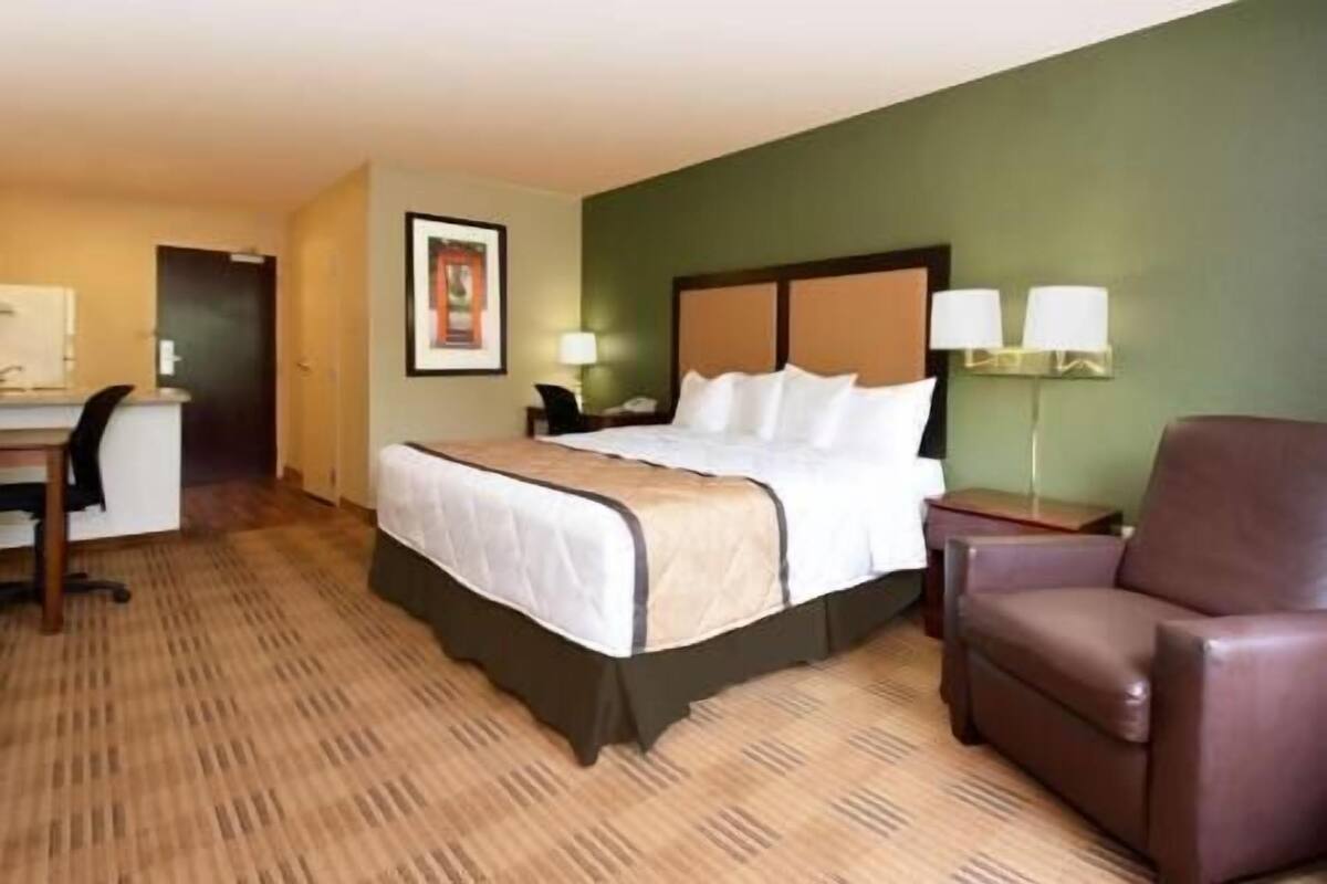 Une chambre d’hôtel avec un lit, un bureau, une chaise et une lampe.