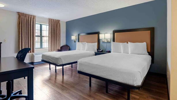 Une chambre d’hôtel avec deux lits, un bureau et une chaise.