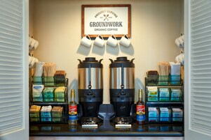 Una estación de café con dos máquinas de café, cápsulas de café y un letrero para Groundwork Organic Coffee.