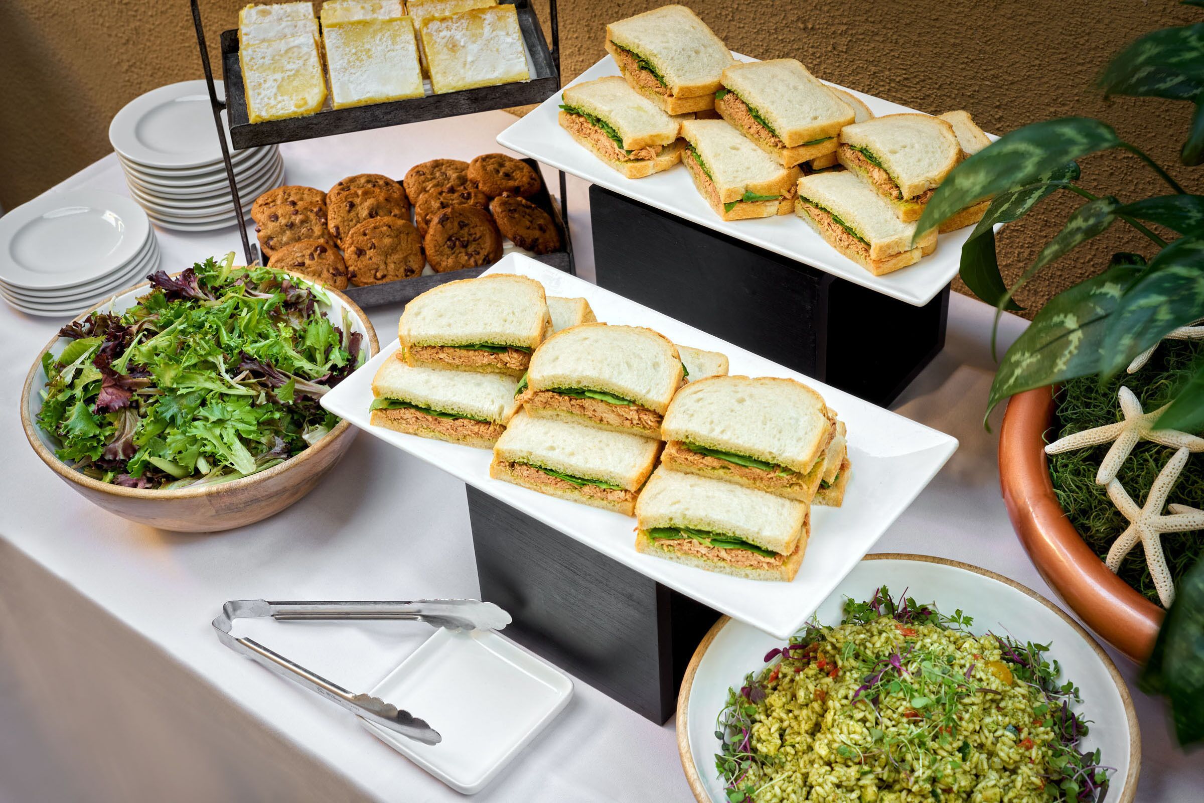 A buffet table with sandwiches, salads, and cookies.