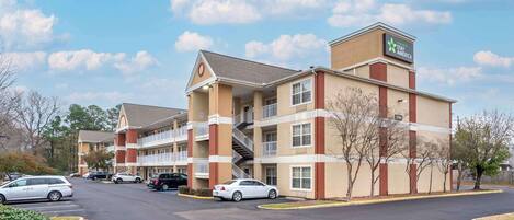 A Stay America hotel with a two-story structure, multiple balconies, and a parking lot with several cars.