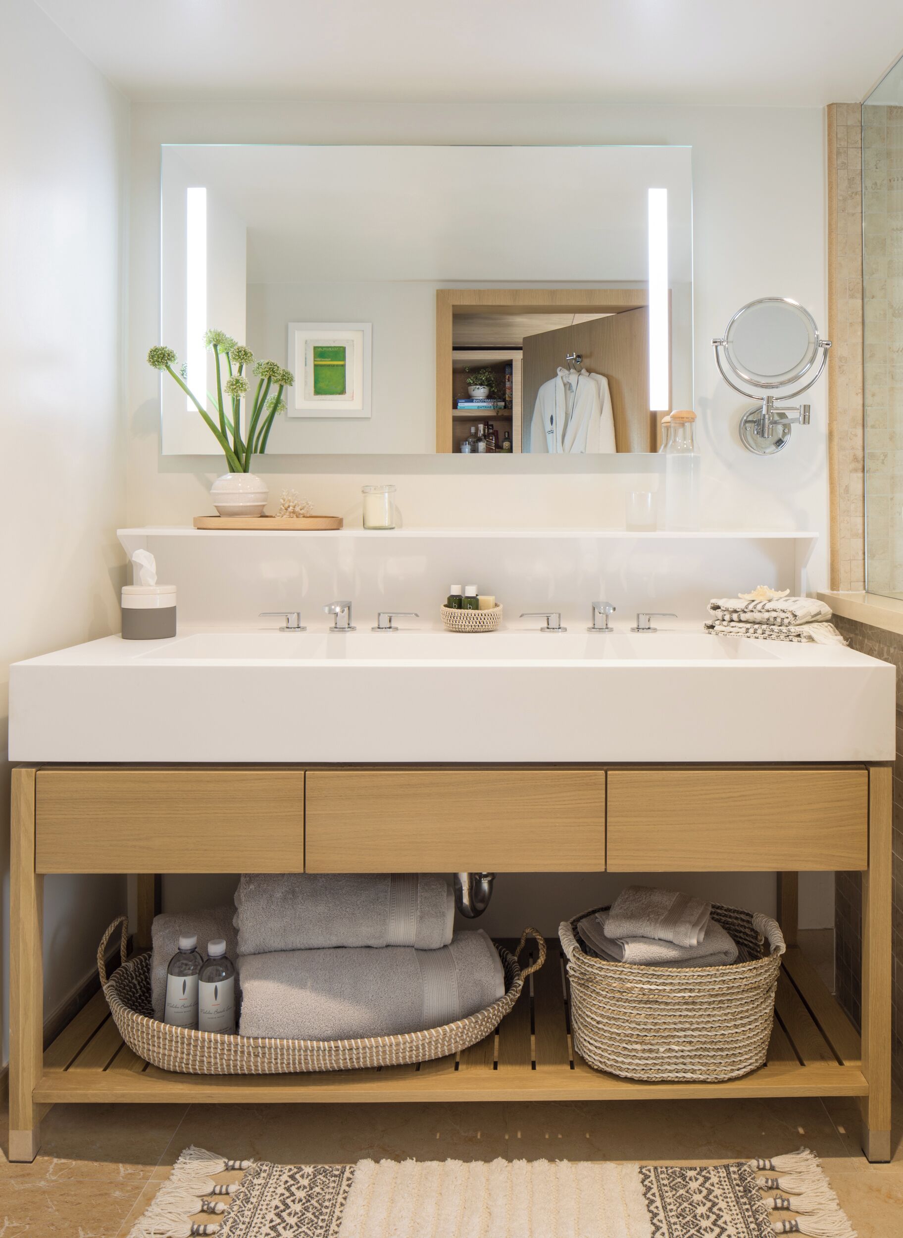 A modern bathroom with a large mirror, two sinks, and a wooden vanity.
