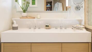 A modern bathroom with a large mirror, two sinks, and a wooden vanity.