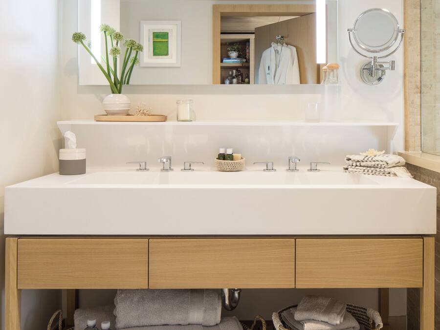 A modern bathroom with a large mirror, two sinks, and a wooden vanity.