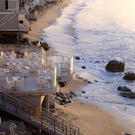 A beachfront hotel with outdoor seating and a pool area.
