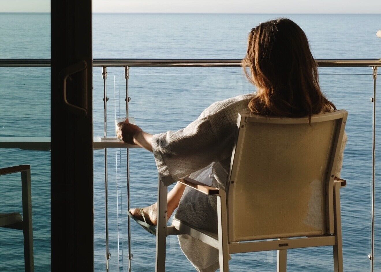Une personne assise à une table, avec vue sur la mer.