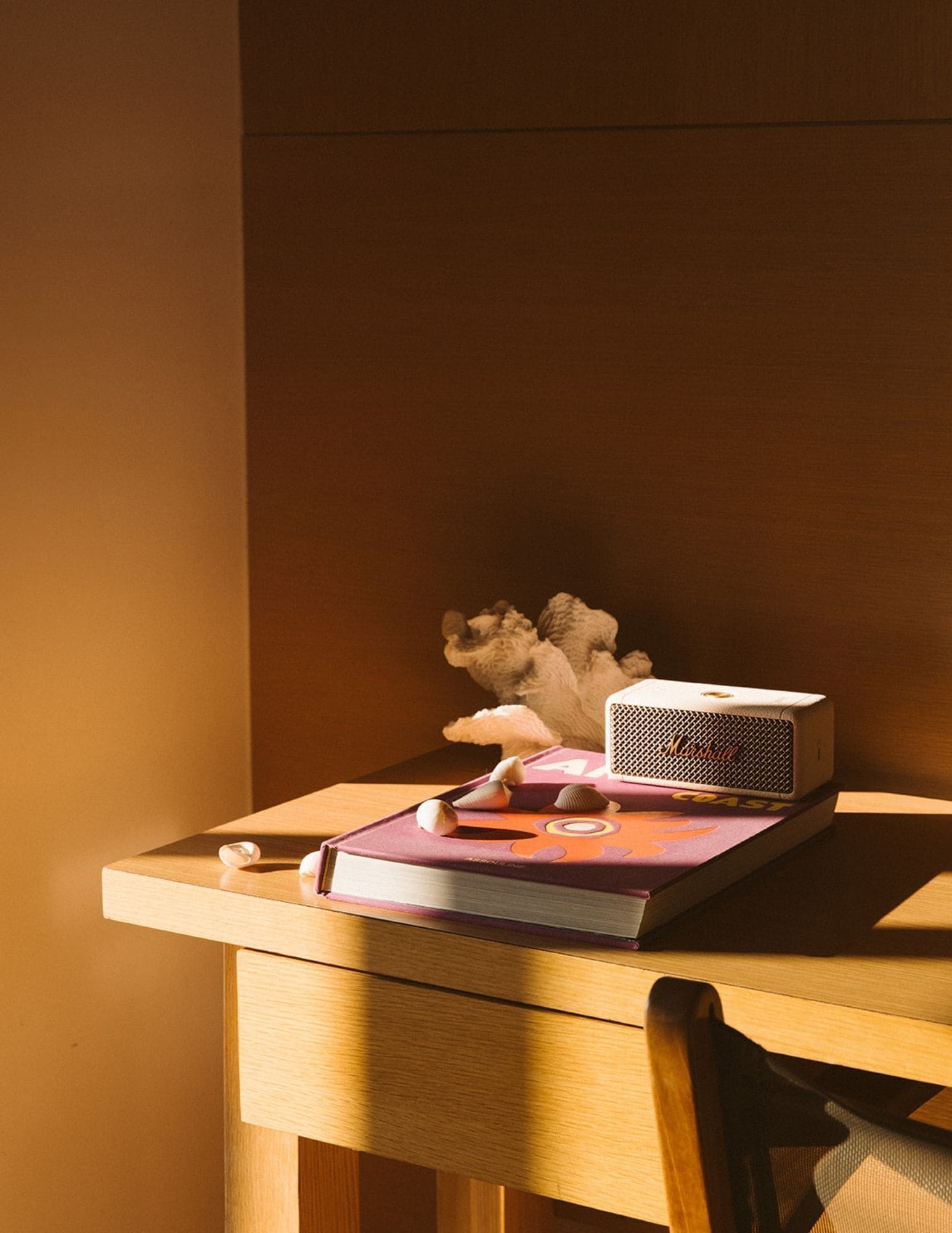 A wooden desk with a laptop, a book, and a small sculpture.