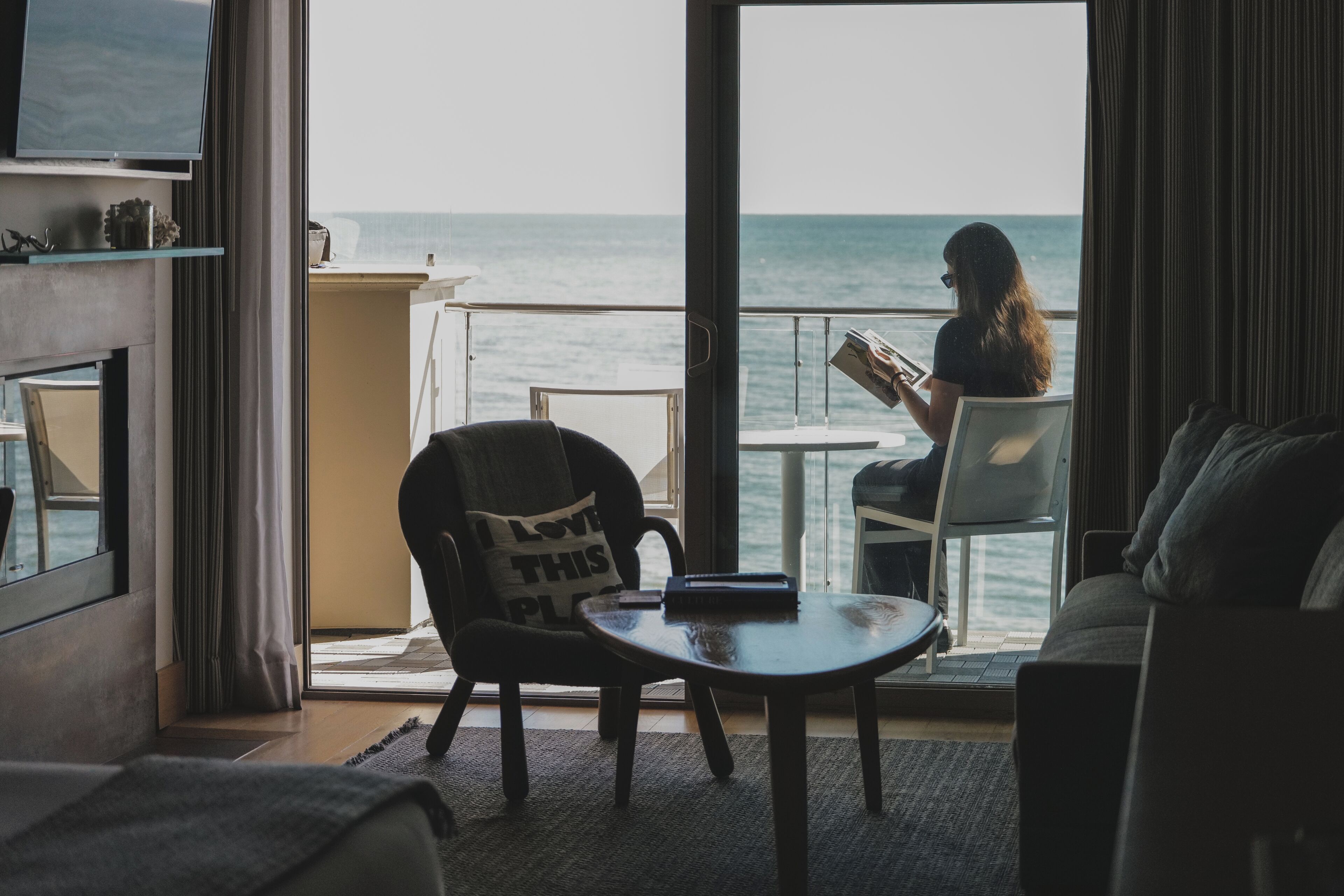 Habitación con vista al mar, una silla con almohada, una mesa y un sofá.