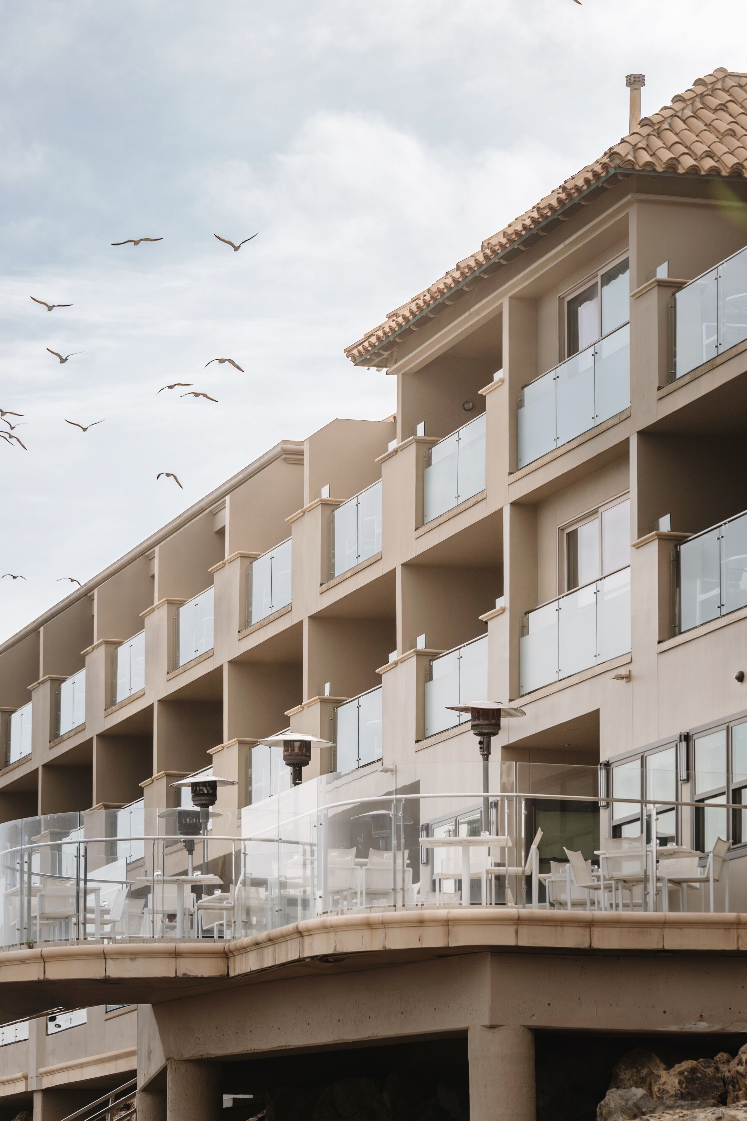 Un hotel de varios pisos con balcones, asientos al aire libre y vista al cielo.