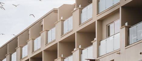 Un hotel de varios pisos con balcones, asientos al aire libre y vista al cielo.