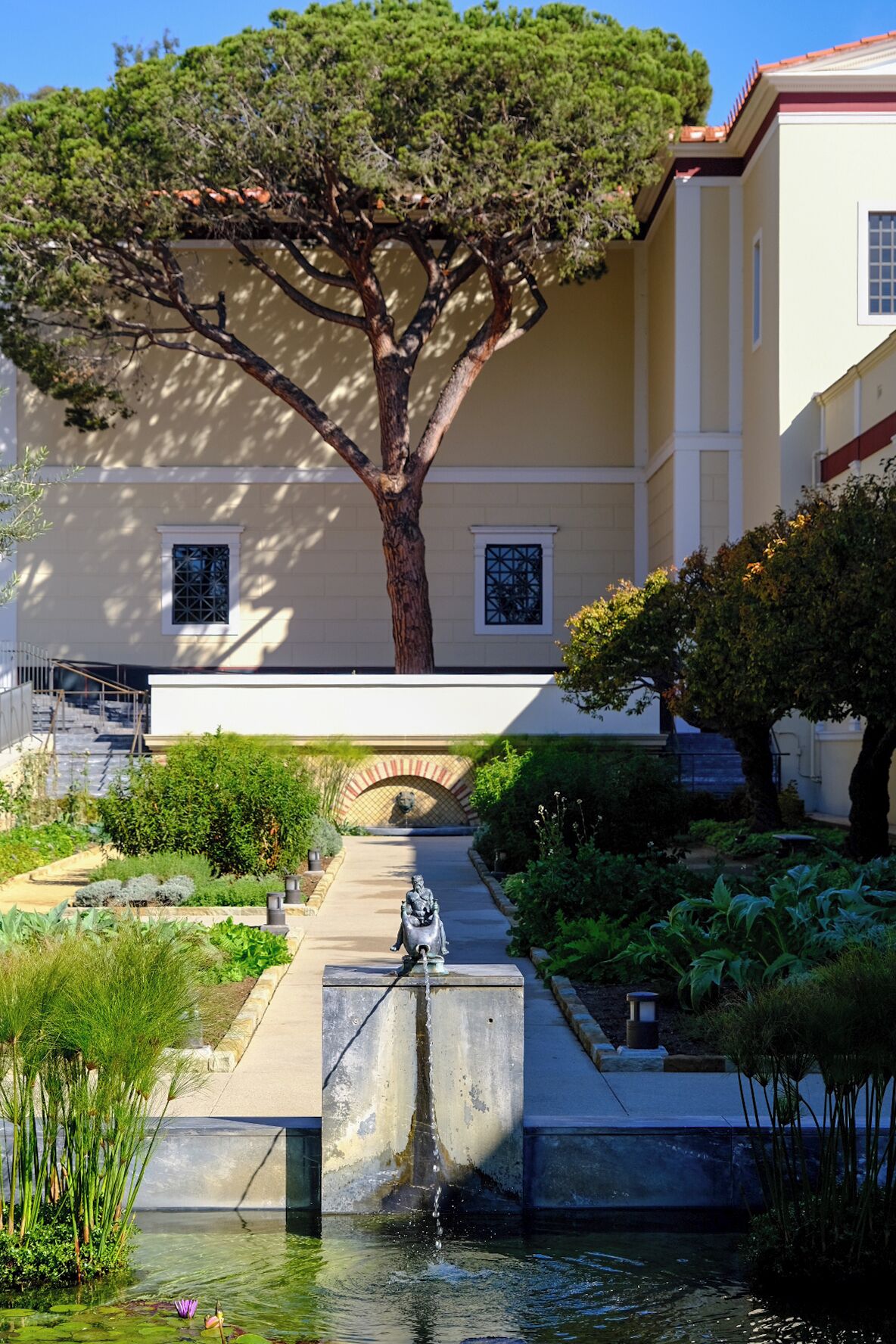 A courtyard with a large tree, a statue, and a water feature.