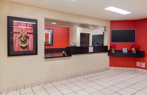 A reception area with a red wall, a framed number 4, a reception desk, and a sign that says "THE BEST YOU CAN COME."