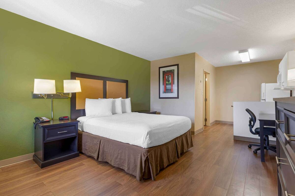 A hotel room with a bed, bedside tables, a desk, and a chair.