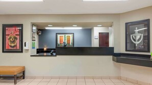 A reception area with a counter, a bench, a framed picture, and a door marked with the number 4. - Extended Stay America Suites Fort Wayne South (Fort Wayne)