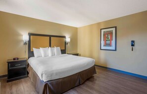 A hotel room with a large bed, two bedside tables, a nightstand, a framed picture on the wall, and a blue accent wall.