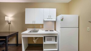 A compact kitchenette with white cabinets, a sink, a microwave, and a refrigerator. - Extended Stay America Select Suites Springfield South (Springfield)