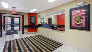 A hotel reception area with a reception desk, a framed artwork, and an exit sign. - Extended Stay America Select Suites Springfield South (Springfield)