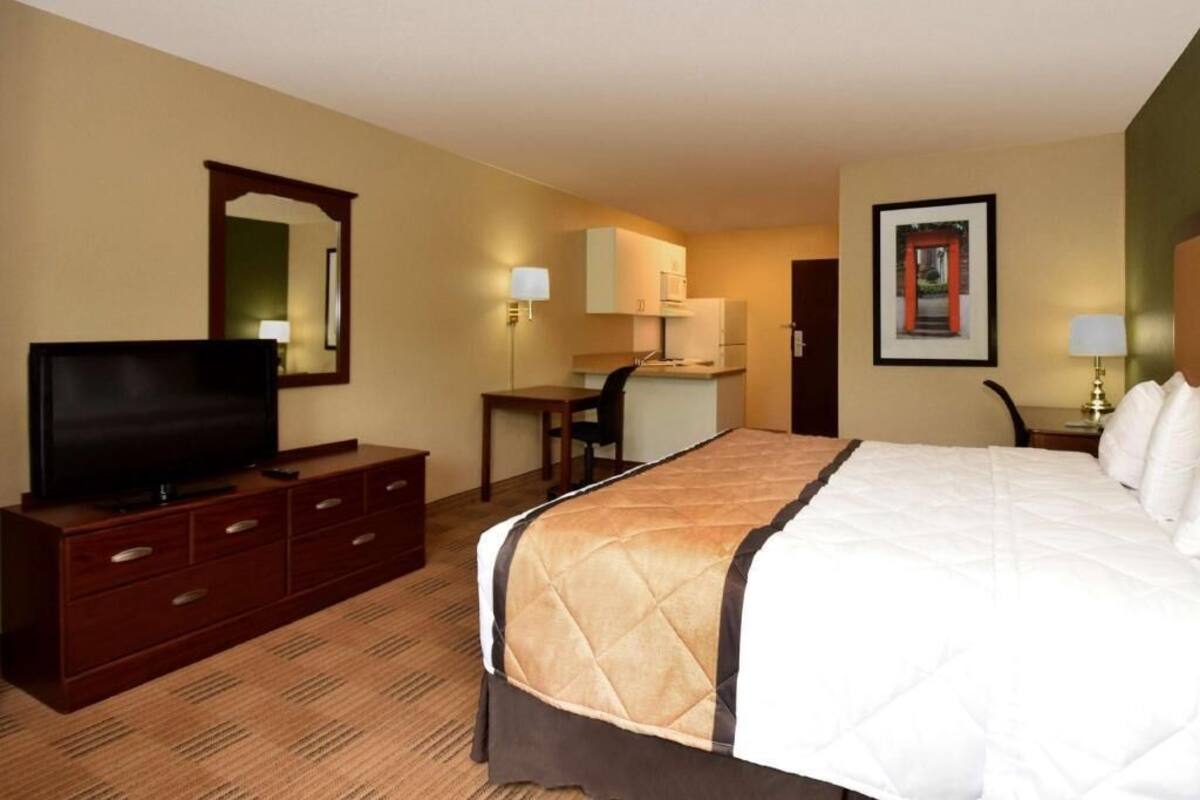 Una habitación de hotel con cama, televisión, escritorio y silla.