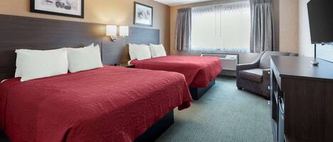 A hotel room with two beds, a desk, a TV, and a window with curtains.